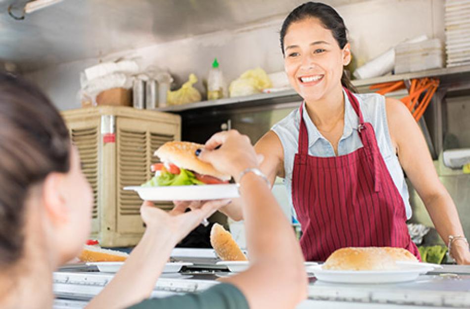 woman handing sandwich to another woman