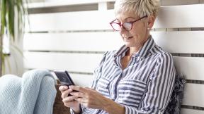 A lady sitting outside scrolling on her phone. 