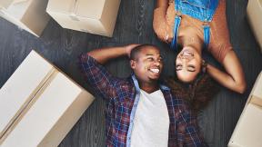 A couple taking a break from moving to lay on the floor together. 